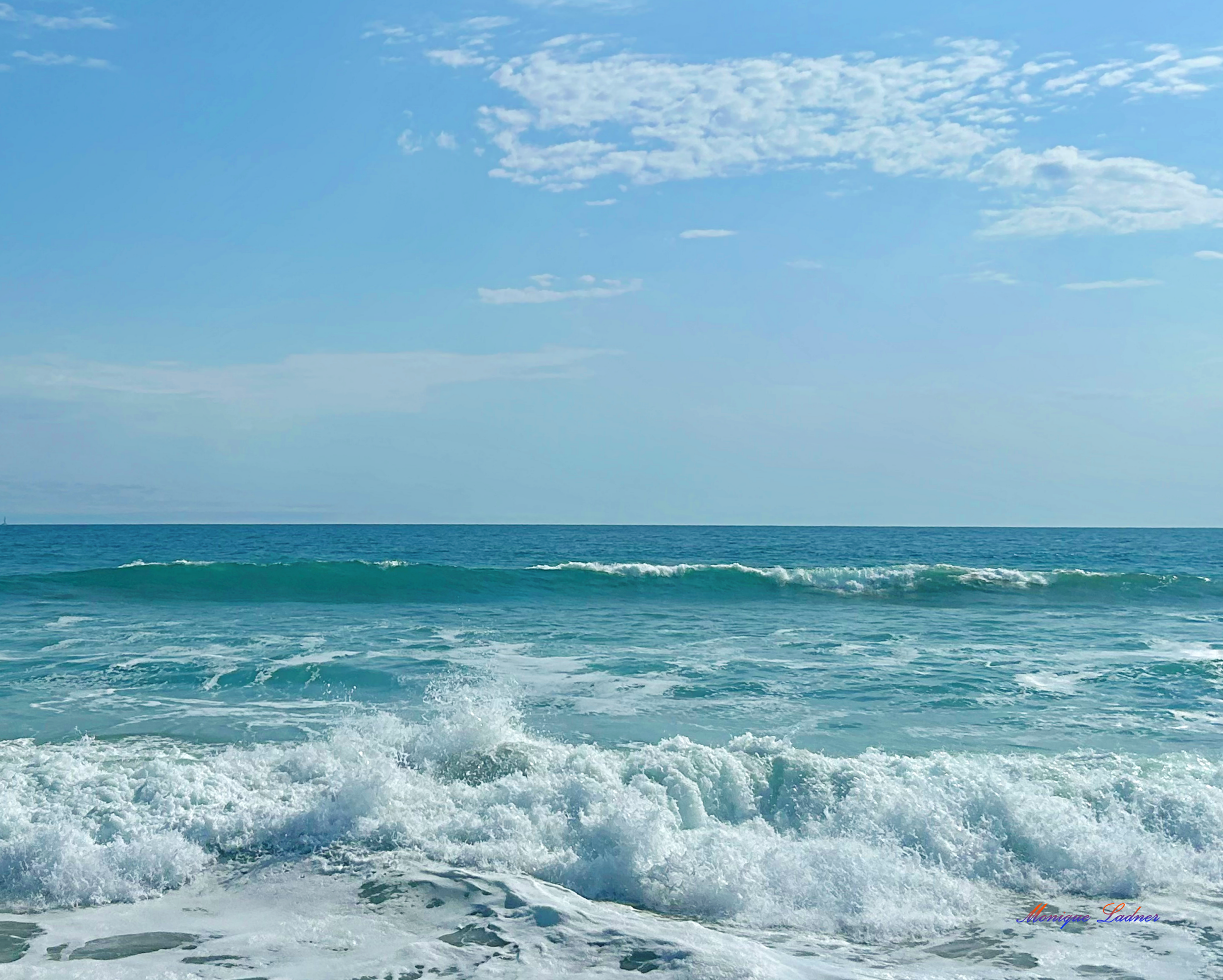 Ladner Art Corner Editorial Photography category. Color landscape photo of the ocean under a blue sky with waves coming in.