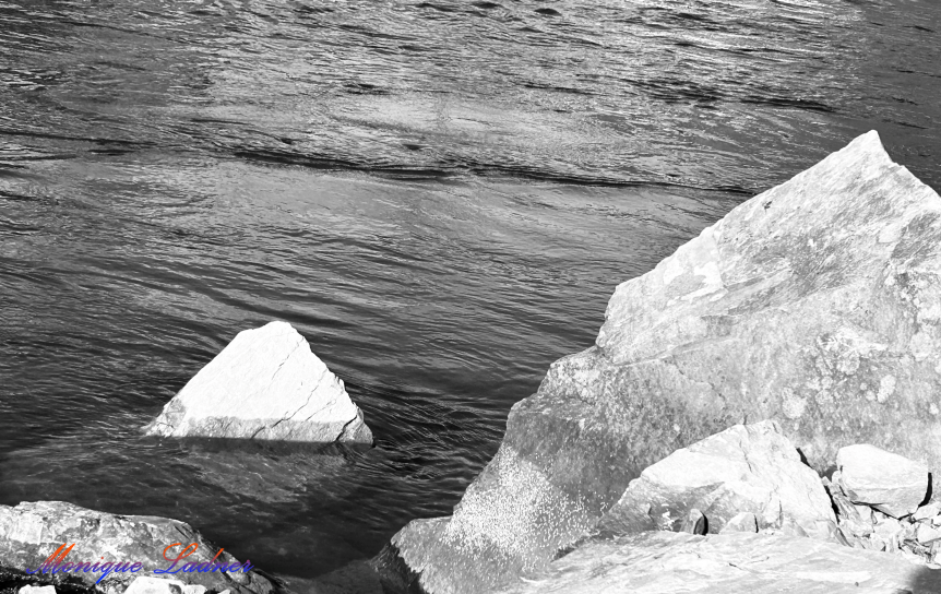 Ladner Art Corner Editorial Photography category. Black and white photo of jagged rocks sticking up out of a water reservoir with light reflections.